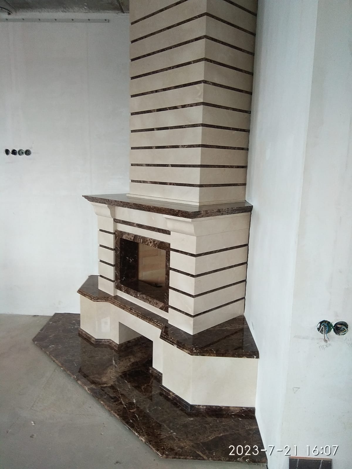 Интересного дизайна мраморный камин с подиумом и коробом в облицовке камнем.